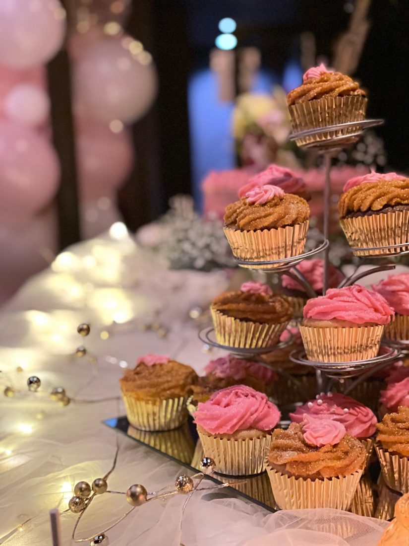 Mesa de cupcakes rosados y dorados en una celebración